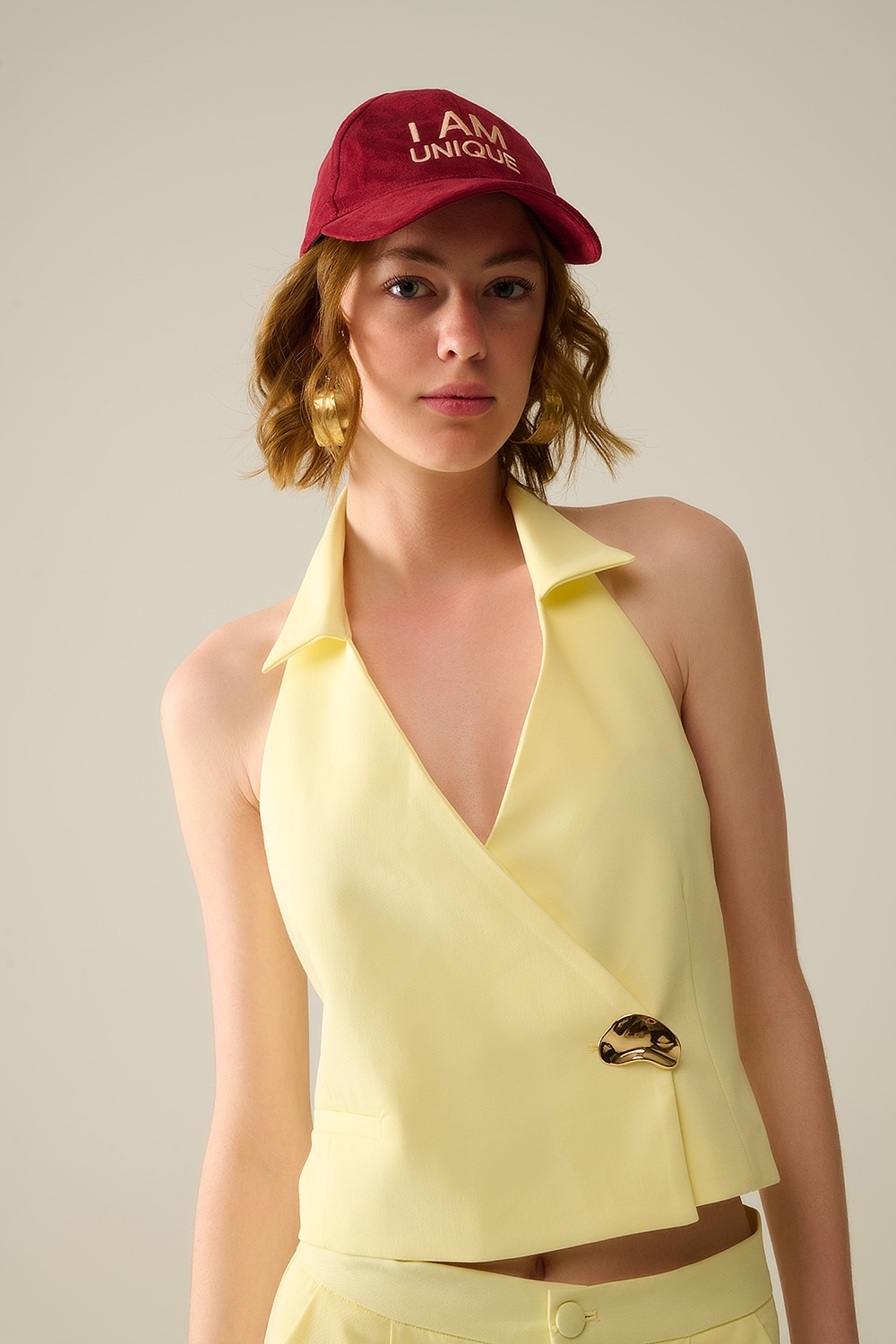 Chaleco envolvente amarillo con bot&oacute;n dorado detallado