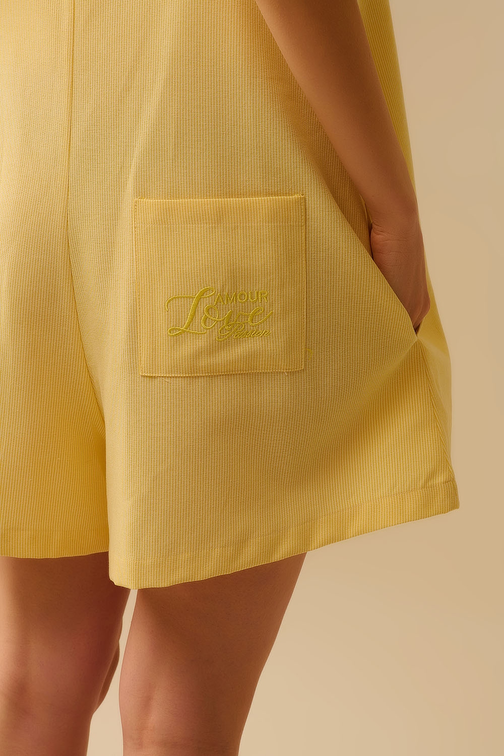 Mono amarillo a rayas con lazos en los hombros y bolsillo trasero