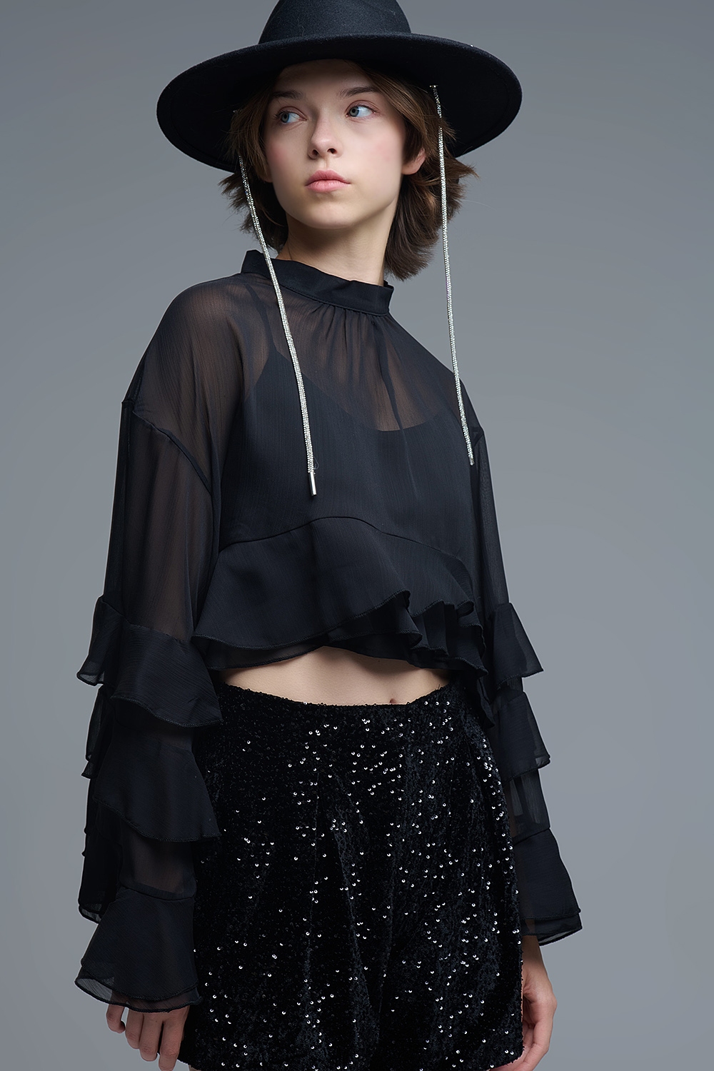 Blusa negra de gasa con volantes y transparencias estilo capa