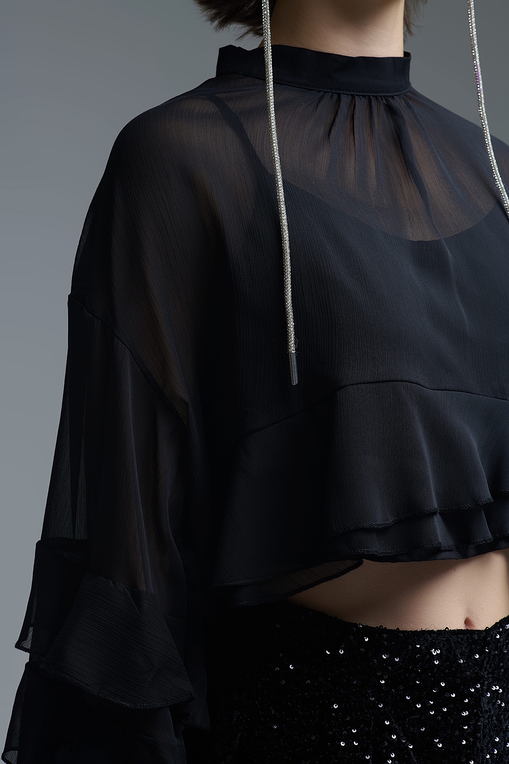 Blusa negra de gasa con volantes y transparencias estilo capa