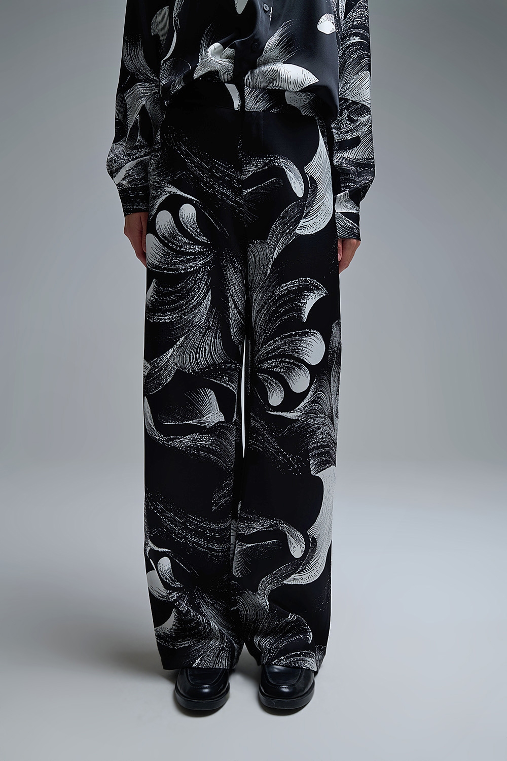 Elegante pantalón negro estampado de pata ancha en tejido satinado Elegante pantalón negro estampado de pata ancha en tejido satinado