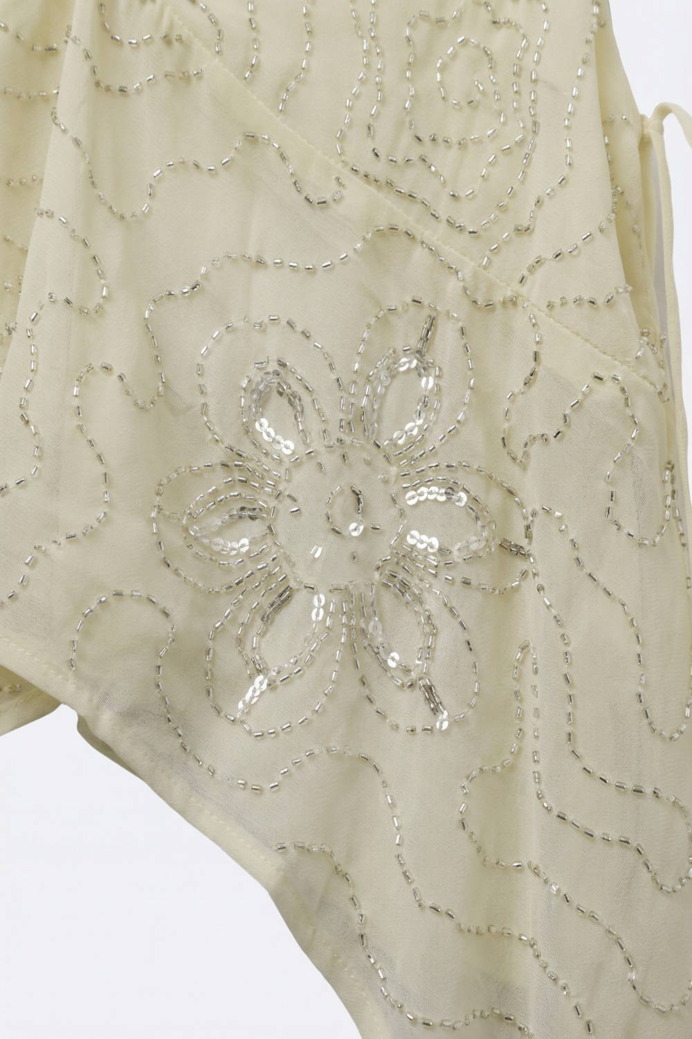 Blusa de gasa color crema con bajo asimétrico y adornos de cuentas Blusa de gasa color crema con bajo asimétrico y adornos de cuentas