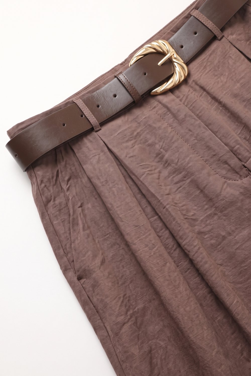 Pantalones anchos con textura marrón brillante con cinturón y detalle de pliegues Pantalones anchos con textura marrón brillante con cinturón y detalle de pliegues