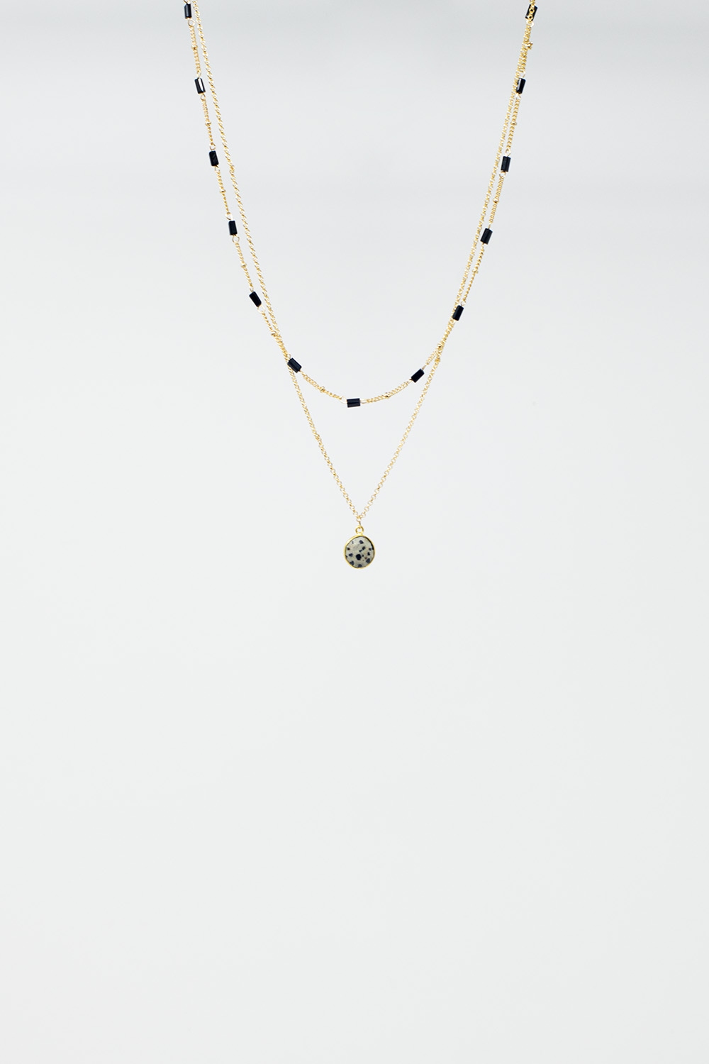 Collar corto 2 en 1 de oro con cuentas negras y piedra jaspeada blanca.