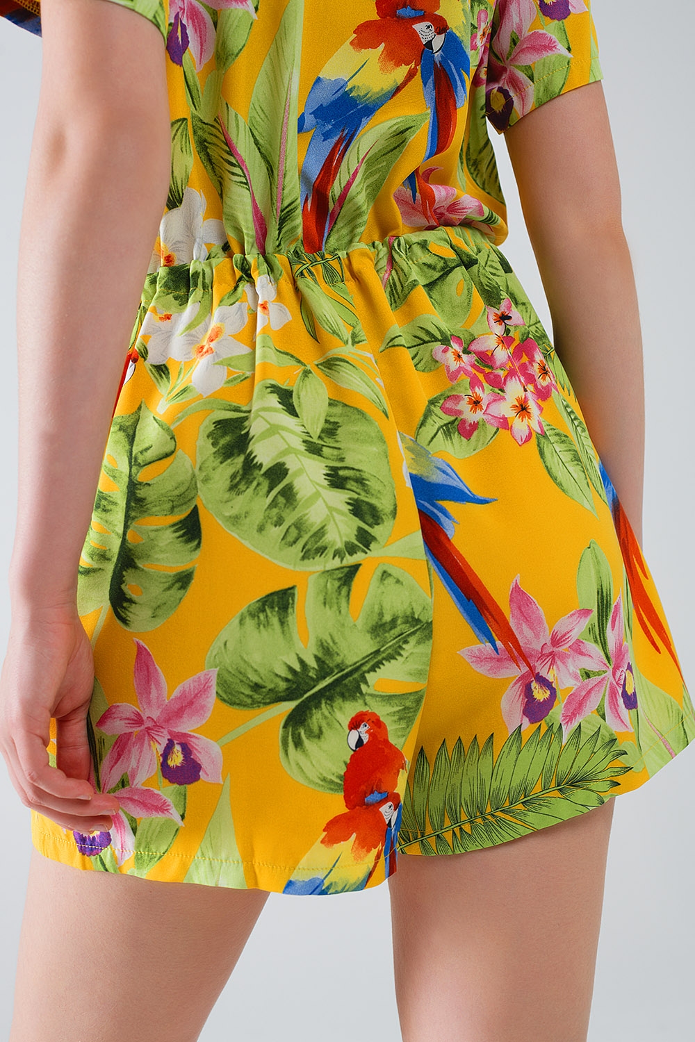 Mono corto amarillo con estampado tropical y cierre de cord&oacute;n